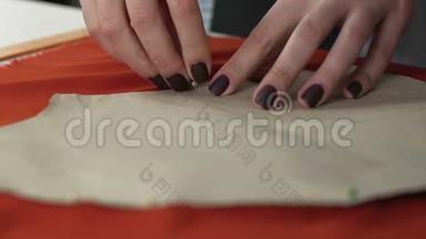 裁缝女士用<strong>别针</strong>将图案贴在橙色织物上，裁剪工艺